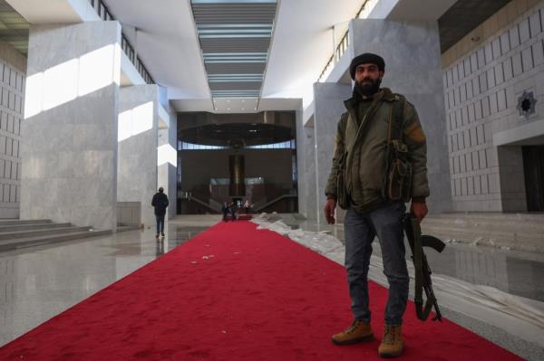 fighters walk in the Syrian presidential palace in Damascus on December 8, 2024, after Islamist-led rebels declared that they have taken the Syrian capital in a lightning offensive,