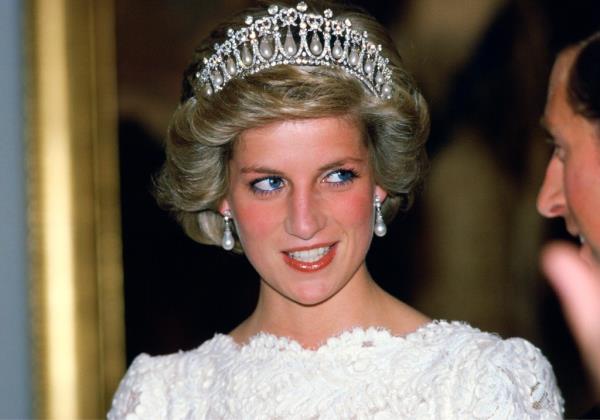 Diana, Princess of Wales, in a taffeta and lace gown with Queen Mary's diamond and pearl tiara, co<em></em>nversing with her husband at the British embassy.