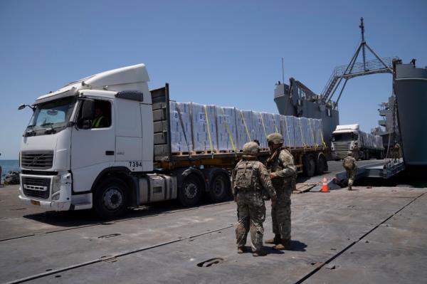  U.S. Army soldiers stand next to trucks arriving loaded with humanitarian aid at the U.S.-built floating pier Trident before reaching the beach on the coast of the Gaza Strip