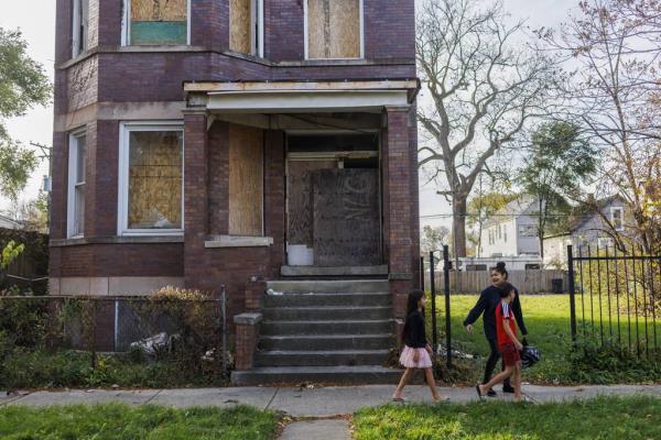 Yuledy and Pedro Mendez walk with their older brother's partner, Yolexi Cubillan, 19, past a boarded-up building on their way home after shopping for food in the Englewood neighborhood on Nov. 6, 2023, in Chicago. 