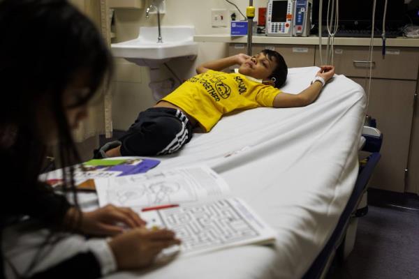 Yuledy and her brother Pedro keep busy while seeking treatment in the pediatrics department with their mother at Stroger Hospital on Nov. 21, 2023.