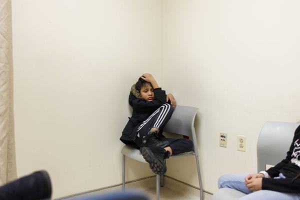 After waiting for hours at Stroger hospital, Pedro sits in the corner of the room.