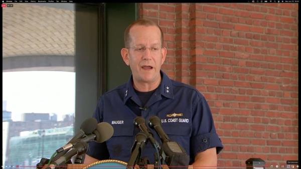  Rear Adm. John Mauger speaks at a podium during a press conference. 