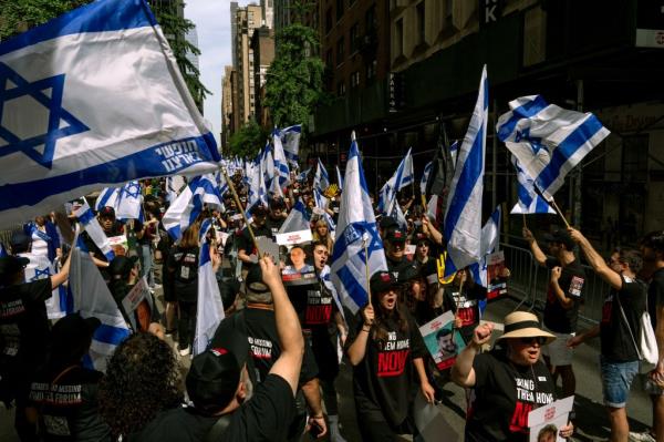 People, including families of hostages, walking through a sea of Israeli flags ahead of the Israel Day parade on Fifth Avenue, New York City on June 2, 2024
