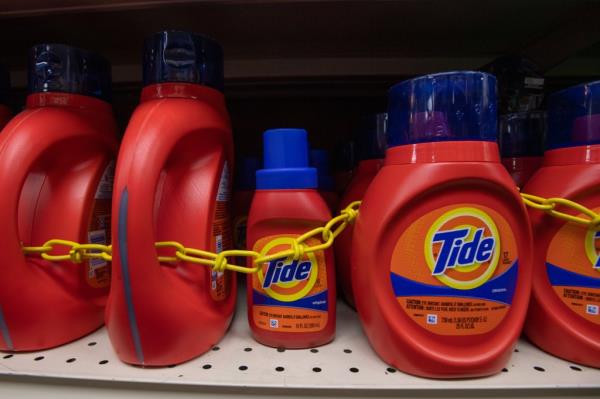 Tide detergent locked down with a yellow chain on a shelf