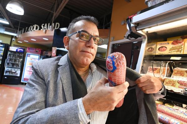 Carlos Collado, demo<em></em>nstrating how thieves steal salami, said some crooks are getting violent with his grocery stores' employees. 