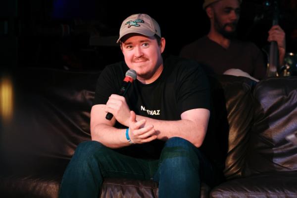 Comedian Shane Gillis holds a microphone. 