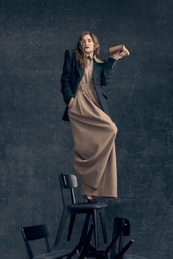 Kathryn Hahn standing on chairs.