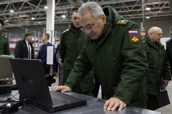 Russian Defence Minister Sergei Shoigu looking at a computer while inspecting drone production.