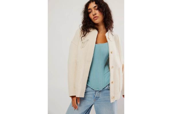 A woman in a creme bomber jacket 