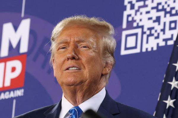 Do<em></em>nald Trump in a suit and tie, speaking into a microphone while standing on a podium at a political rally in Las Vegas.