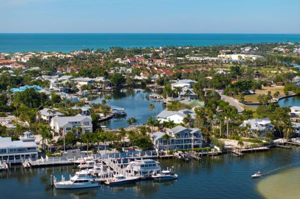 Wealthy neighborhood in small town Boca Grande, Florida with expensive waterfront houses between green palm trees. Development of US premium housing.