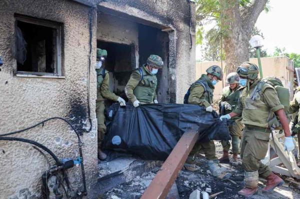 Israeli soldiers remove the body of a compatriot, killed during an attack by terrorists, in Kfar Aza, south of Israel bordering the Gaza Strip.