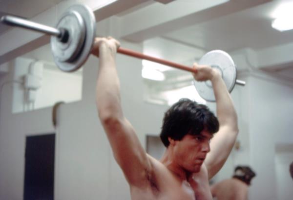 Christopher Reeve lifting a large weight. 