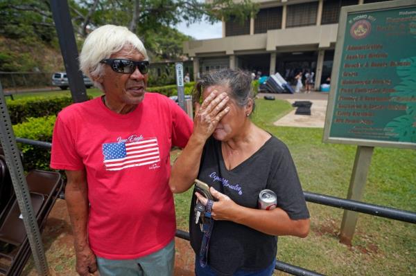Myrna and Abraham Ah Hee react as they stand in front of an evacuation center at the War Memorial Gymnasium after looking for Abraham's brother. 