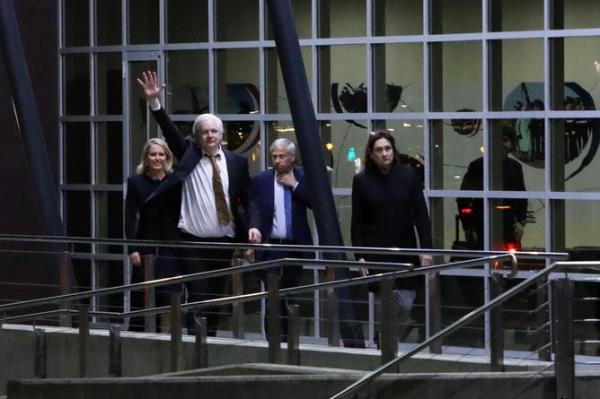 Julian Assange waves as he arrives at Canberra Airport.