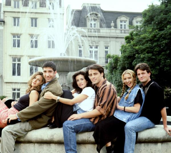 Cast of 'FRIENDS' sitcom, including Jennifer Aniston, David Schwimmer, Courteney Cox Arquette, Matt LeBlanc, Lisa Kudrow, and Matthew Perry, sitting on a fountain in NYC.