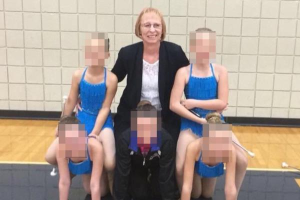 slagle, smiling and looking at the camera, with five young twirlers whose are obscured