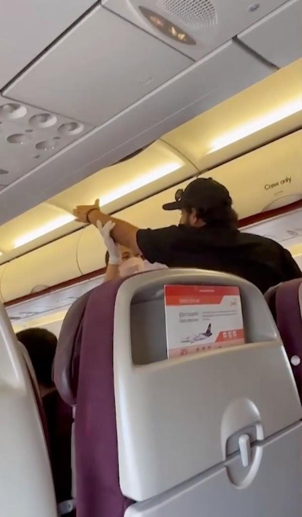 The unruly passengers is seen getting his extended arm grabbed by a flight attendant.