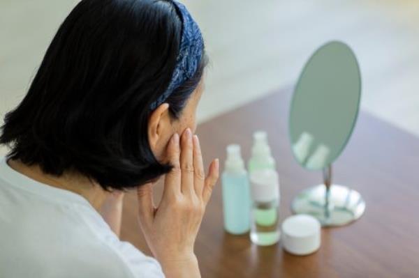 older woman looking at her dry skin, look better after 40