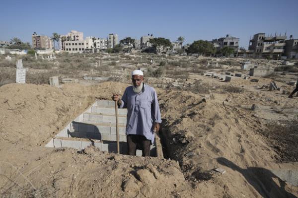Palestinian grave digger Sa’di Baraka pauses while digging new graves in a cemetery in Deir al-Balah, Gaza Strip.