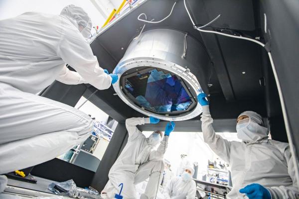 Three people installing a lens on the Rubin camera
