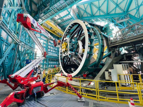 People standing on a crane working on a large telescope