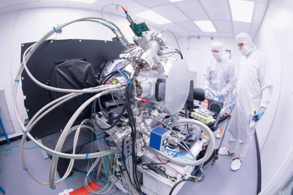 People standing next to machinery in a white room