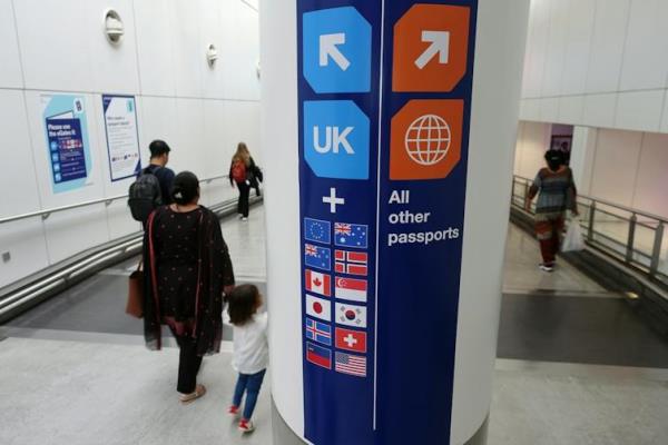 Families walk past a passport co<em></em>ntrol sign in an airport that points people with UK, EU and some other European passports in a different direction to all other passports.