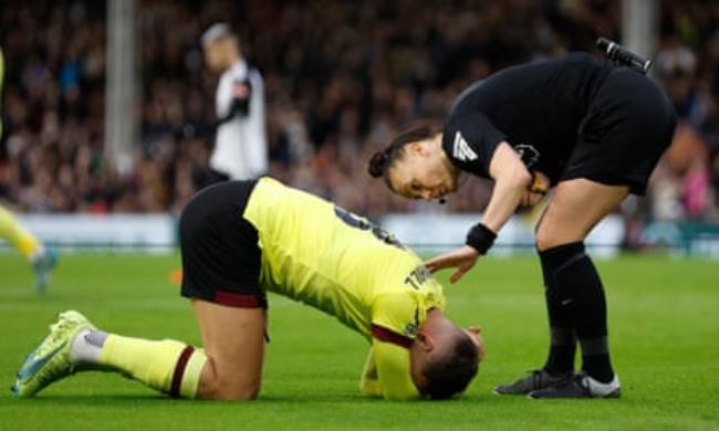 Burnley's Josh Brownhill reacts after sustaining an injury as referee Rebecca Welch looks on.