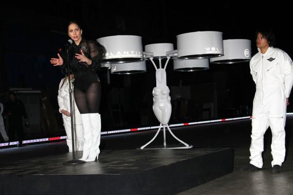 Lady Gaga speaking at a press co<em></em>nference with her flying dress behind her