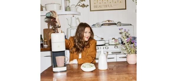 White Beautiful Perfect Grind Programmable Single Serve Coffee Maker on table with Drew Barrymore